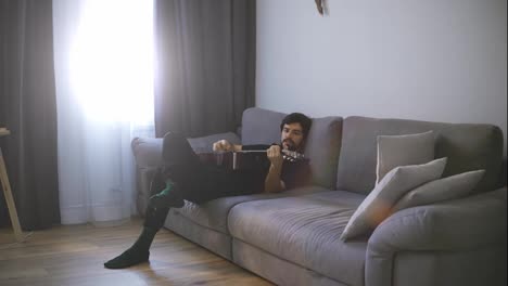 A-young-man-relaxing-on-the-couch-and-plays-the-guitar