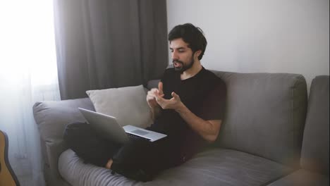 Man-sitting-on-sofa-and-making-a-video-call,-gesturing
