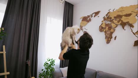 A-young-man-plays-with-a-cat-and-holds-it-and-toss-up