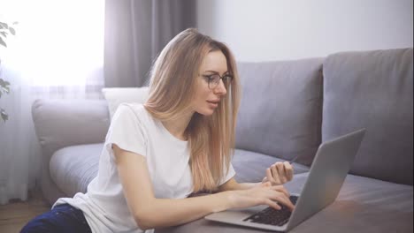 Blonde-woman-sitting-on-the-floor,-pays-for-purchases-online-with-a-credit-card-and-laptop