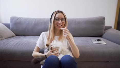 Webcam-view-woman-in-headphones-hugs-cat-shoots-video-for-blog-with-pet