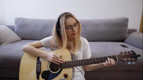 Woman-plays-the-guitar-at-her-home,-happily-having-fun-playing-guitar-and-singing