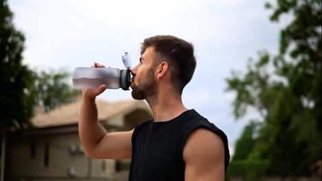 Portrait-of-thirsty-sport-man-drinking-mineral-water-after-outdoor-workout