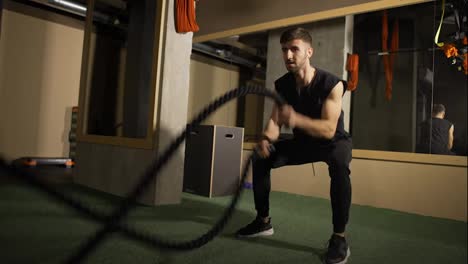 Strong-athlete-doing-battle-rope-exercise-at-crossfit-gym