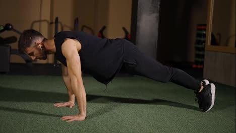 Fitness-guy-strengthening-arm-muscle-with-push-ups-during-intense-workout-at-gym