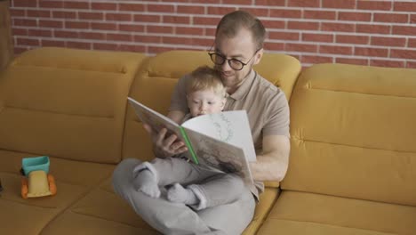 Father-reading-book-aloud-to-cute-son-at-home