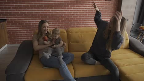 Two-blonde-women-play-with-a-child-by-tickling-him-on-sofa