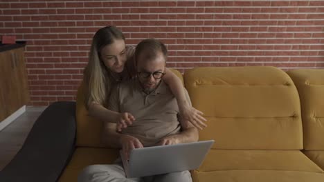 Freelancer-kissing-back-the-cheek-of-cheerful-woman-near-laptop