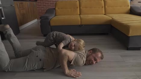 Father-happy-playing-with-his-son-on-the-back-at-living-room