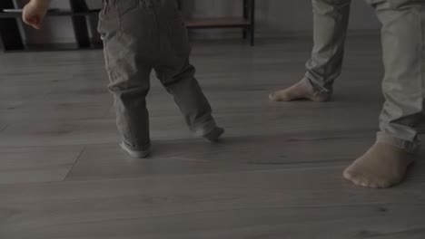 Cropped-footage-of-toddler-boy-walking-around-at-home-between-mother-and-father