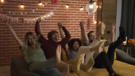 Diverse-people-in-casual-wear-in-living-room-jumping-on-sofa-together-and-laughing