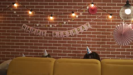 Kreative-Freunde-überraschen-Die-Geburtstagsperson,-Die-Vom-Sofa-Aus-Erscheint