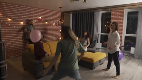 Group-of-people-at-living-room-playing-with-balloon,-have-fun-together