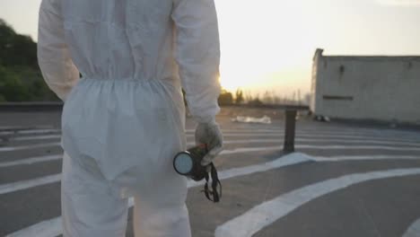 Unrecognizable-worker-in-protective-suit-walks-with-mask-and-respirator-in-hands