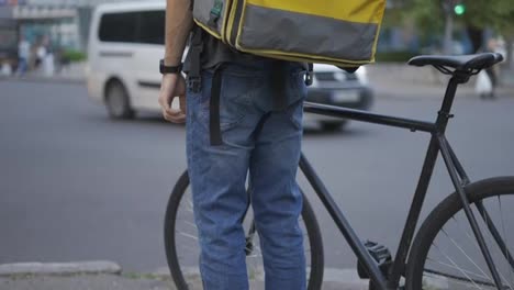 The-delivery-standing-with-bicycle,-waiting-for-city-light-traffic