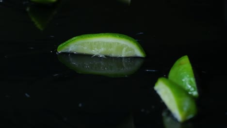 Limes-and-lemon-slices-rise-up-bouncing-water-droplets-and-reflecting-black-background
