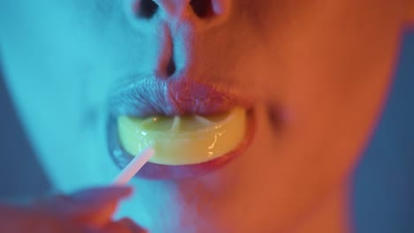 Rack-focus-young-woman-sensually-licking-a-yellow-lollipop-in-studio-light