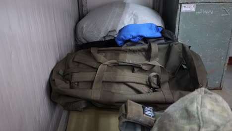 Soldier-putting-his-personal-effects-on-a-bed,-army-backpack-and-uniform