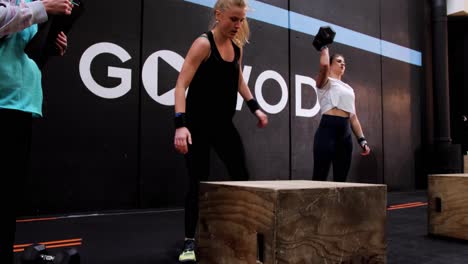 a-young-blonde-Caucasian-woman-jumping-on-a-wooden-crate-during-a-crossfit-competition-called-"box-jump"