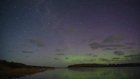 Dramatic-timelapse-capturing-beautiful-auroral-activity-at-the-coastal-environment-in-New-Zealand,-aurora-australis-with-vibrant-green,-red-and-purple-displaying-on-dark-night-sky-with-moving-clouds