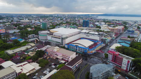 Aerial-Drone-Establishing-Shot-Of-Large-Shopping-Mall-In-South-East-Asia-City-Surrounded-By-Urban-Area-During-Cloudy-Day