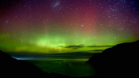 Dramatic-timelapse-shot-of-Aurora-Australis-activity,-capturing-atoms-emit-visible-light-of-distinct-wavelengths-and-create-green,-red-and-purple-colours-display-on-the-sky-at-Nugget-Point-New-Zealand