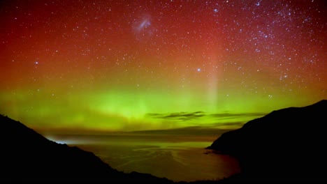 Timelapse-shot-capturing-nature-phenomenon,-Southern-light-Aurora-illuminate-the-night-sky,-display-dynamic-patterns-of-brilliant-lights-with-red-and-green-colours-at-Nugget-Point-New-Zealand