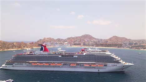 An-aerial-drone-flies-over-the-Carnival-Panorama-cruise-ship-looking-down-upon-the-outdoor-movie-theater-and-water-park-while-anchored-in-the-bay-of-Cabo-san-Lucas,-Mexico