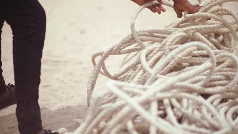 close-up-of-unidentifiable-Fisherman's-hands-gathering-thick-fishing-ropes-at-shore