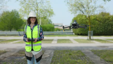 Female-Surveyor-Operating-Professional-Aerial-Drone-In-Car-Park-Wearing-Hi-Vis
