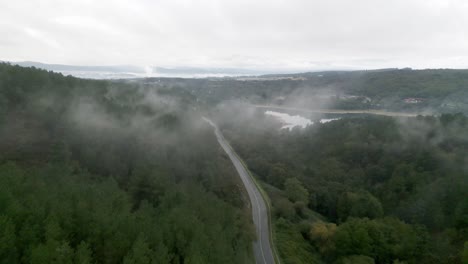 Luftdrohnenaufnahmen-Einer-Einzelnen-Autobahn,-Die-Sich-Durch-Einen-üppigen,-Nebligen-Regenwald-Schlängelt