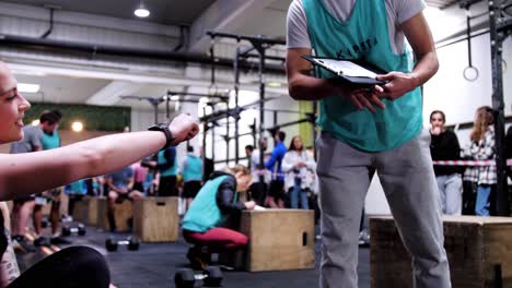 Crossfit-instructor-with-training-log-fist-bumps-Caucasian-female-athlete