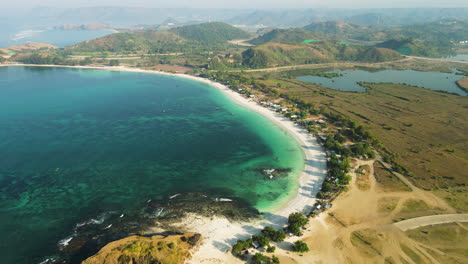 Scenic-aerial-view-of-white-sand-beach-of-Tanjung-Aan-surrounded-by-turquoise-seawater-and-mountains,-Indonesia