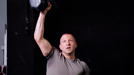 Big-caucasian-fitness-athlete-male-lifting-a-heavy-dumbbell-of-the-ground-in-the-air