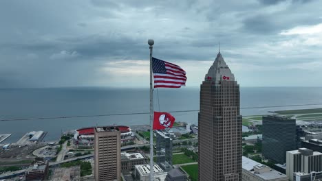 Cleveland,-Ohio-USA,-Aerial-View-of-American-National-Flag-Waving-on-Pole-in-Front-of-Key-Tower-and-Lake-Erie-Coastline