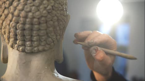 Unerkennbarer-Künstler,-Der-In-Der-Werkstatt-Mit-Einem-Spezialwerkzeug-An-Den-Haaren-Der-Buddha-Statue-Arbeitet