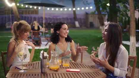 Happy,-three-attractive-women-having-fun-and-dancing-in-the-restaurant-outdoors-in-the-evening-dusk