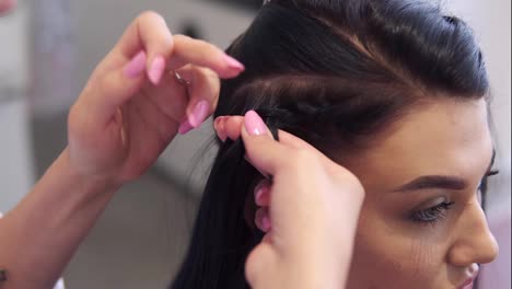Close-up-of-hairdresser-plaiting-braids-to-brunette-girl-in-beauty-salon.-Slow-motion.-Close-up
