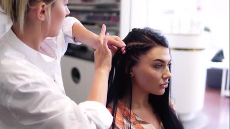 Working-process-of-hairdresser-plaiting-braids-to-brunette-girl-in-beauty-salon.-Slow-motion.-Close-up