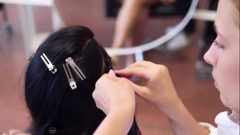 Working-process-of-hairdresser-plaiting-braids-to-brunette-girl-in-beauty-salon.-Slow-motion.-Close-up.-High-angle-view