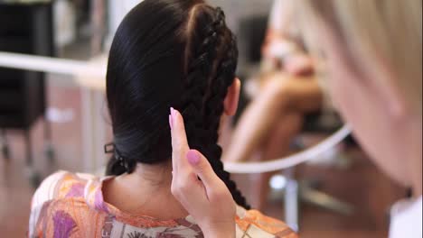 Close-up-female-hairdresser-hands-finishing-volumizing-hairstyle-use-fixing-hairspray-to-girl-customer.-Young-beautiful-woman-having-gorgeous-hairdo-at-beauty-salon.-Slow-motion