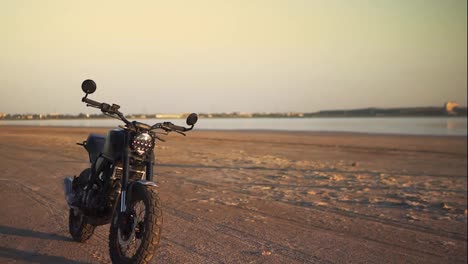 Overview-footage-footage-of-motorcycle-parking-on-the-ground-close-to-the-water-in-sunset,-sunlight-under-water-on-background