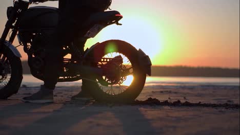 Der-Motorradfahrer-Stößt-Mit-Dem-Hinterrad-Auf-Der-Stelle,-Im-Hintergrund-Ist-Der-Sonnenuntergang-Zu-Sehen