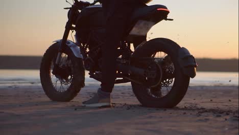 Unrecognizable-motorcyclist-thrusts-on-the-spot-with-the-rear-wheel,-evening-dusk