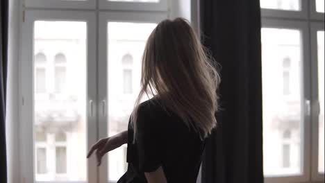 Relaxed-woman-dances-against-the-background-of-the-large-windows-of-her-apartment-in-the-morning