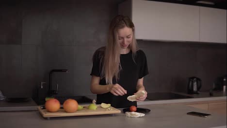 Woman-cleans-pomelo-slice-in-the-kitchen-on-a-counter
