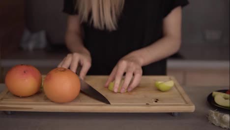 Cropped-view-of-a-woman-cutting-and-clean-green-apple-on-chopping-board