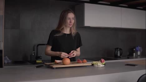 Portrait-of-a-woman-cleaning-grapefruit-peel-on-chopping-board-at-kitchen