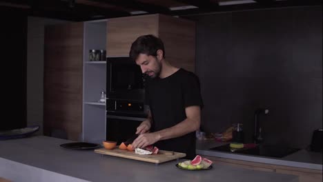 Portrait-of-a-man-cutting-grapefruit-on-chopping-board-and-funny-dances