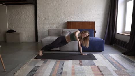 Woman-performing-bodyweight-fitness-training-at-her-apartment-doing-side-plank